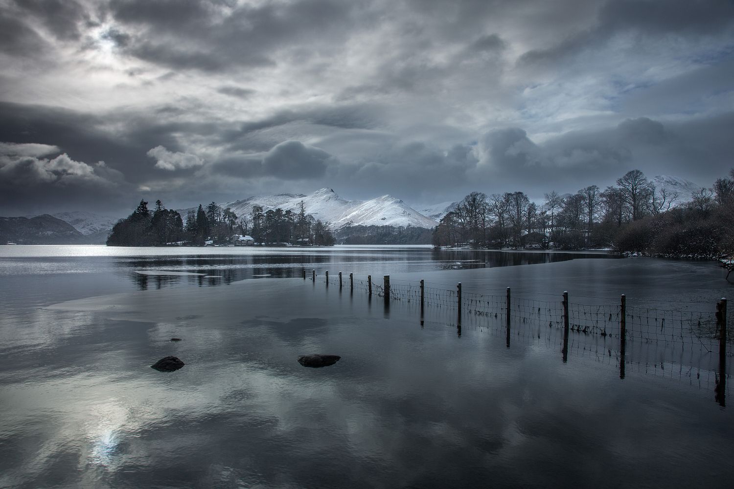 A snow-covered Catbells seen cross Derwentwater bathed in shafts of light